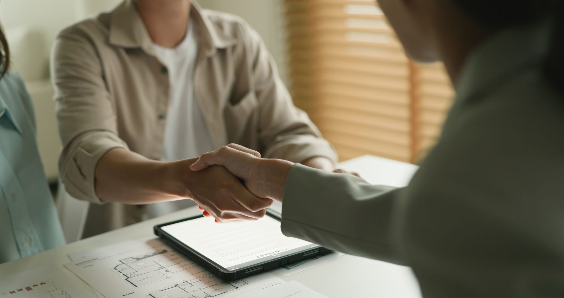 Business Agreement Handshake Across Office Desk with Documents.